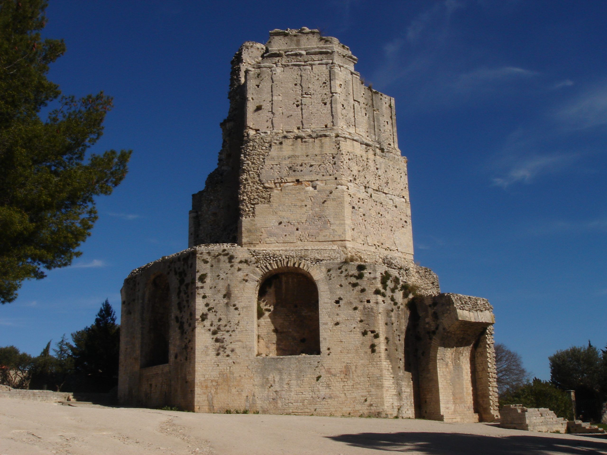 The Tour Magne, a Roman tower in Nîmes, standing in sunlight against a bright blue sky.