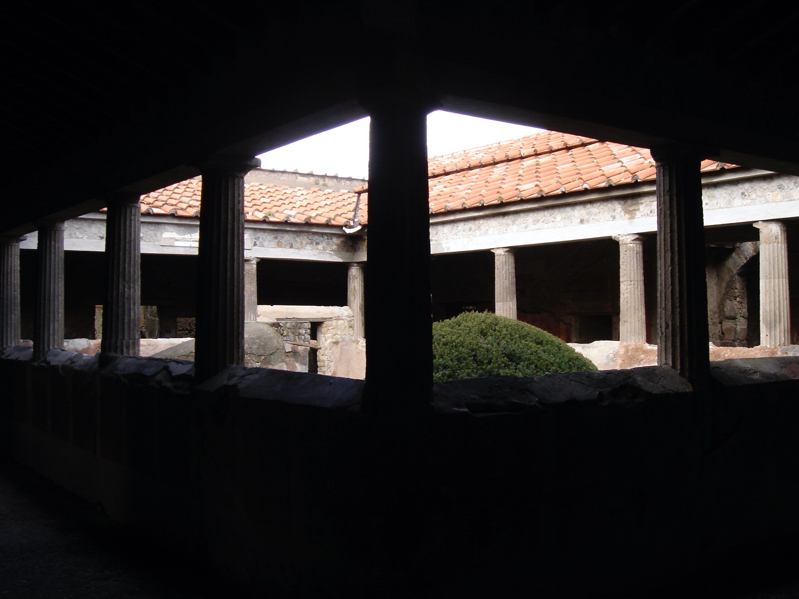 A dark interior space at the Villa of the Mysteries, with brick vaults and light falling in patches on the ancient floor.