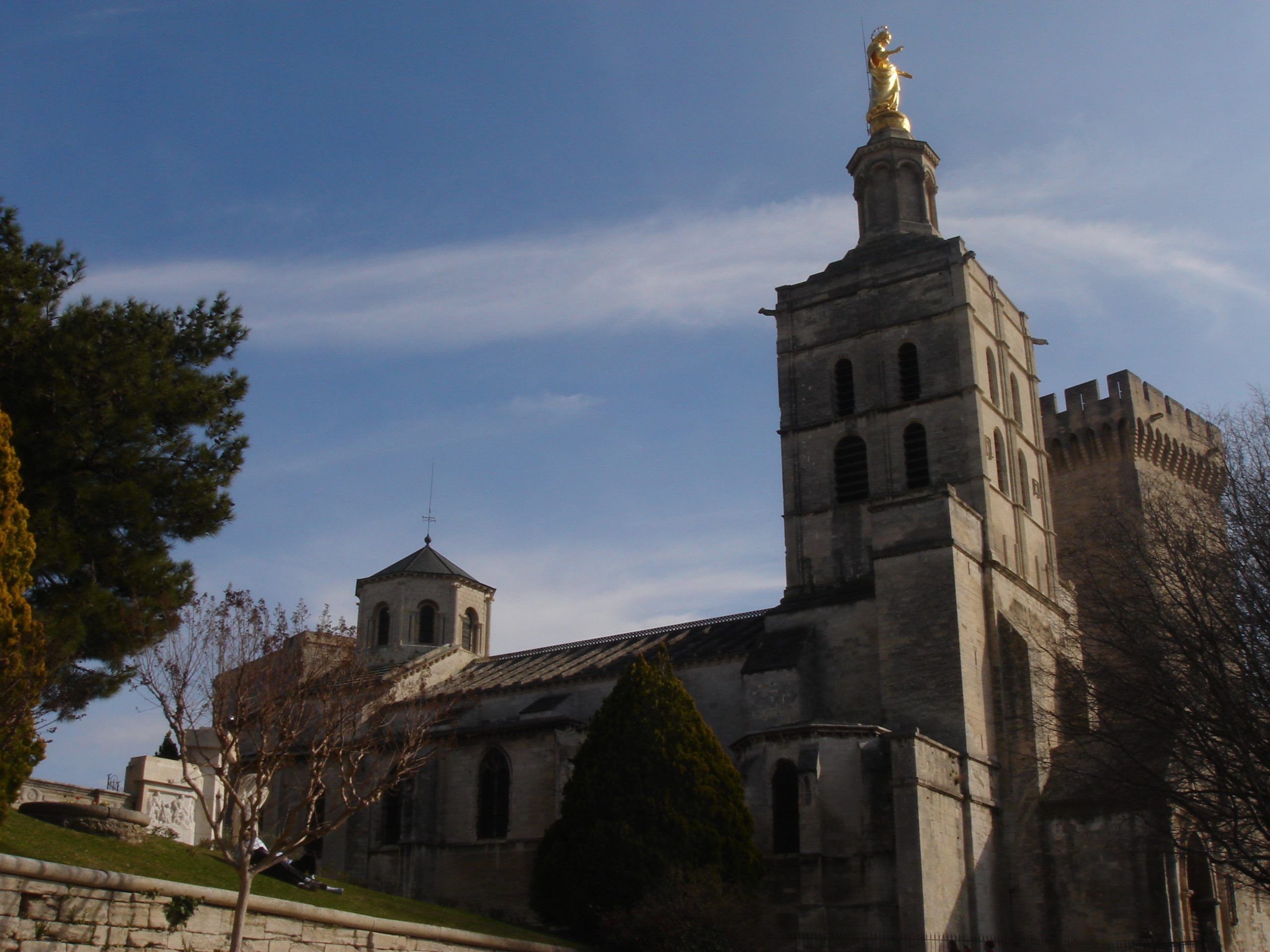 Close-up view of the bell tower of Avignon Cathedral, topped with a gilded statue of the Virgin Mary.