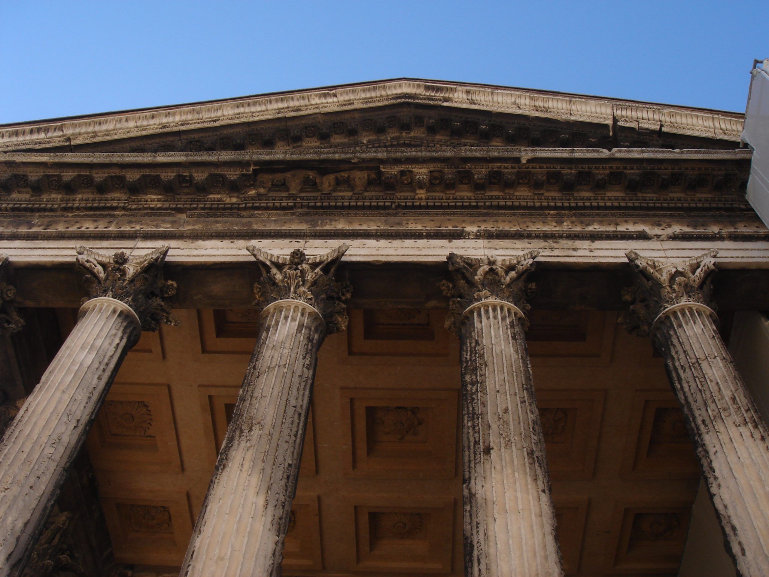 Close-up view of the Corinthian columns and ornate entablature of the Maison Carrée temple in Nîmes.