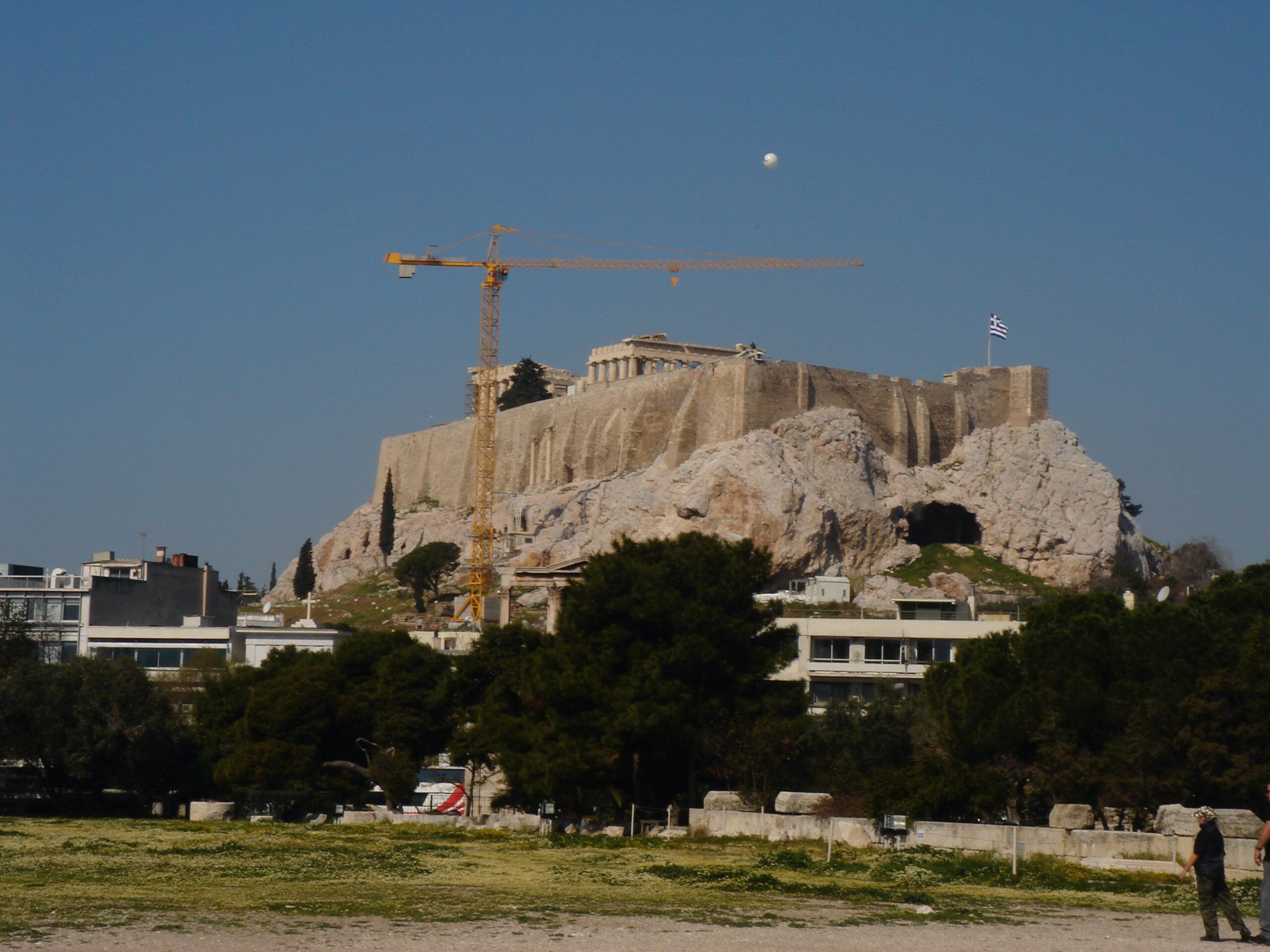 View of the Acropolis from the Temple of Olympian Zeus, with the Parthenon in the center and a large crane beside it.