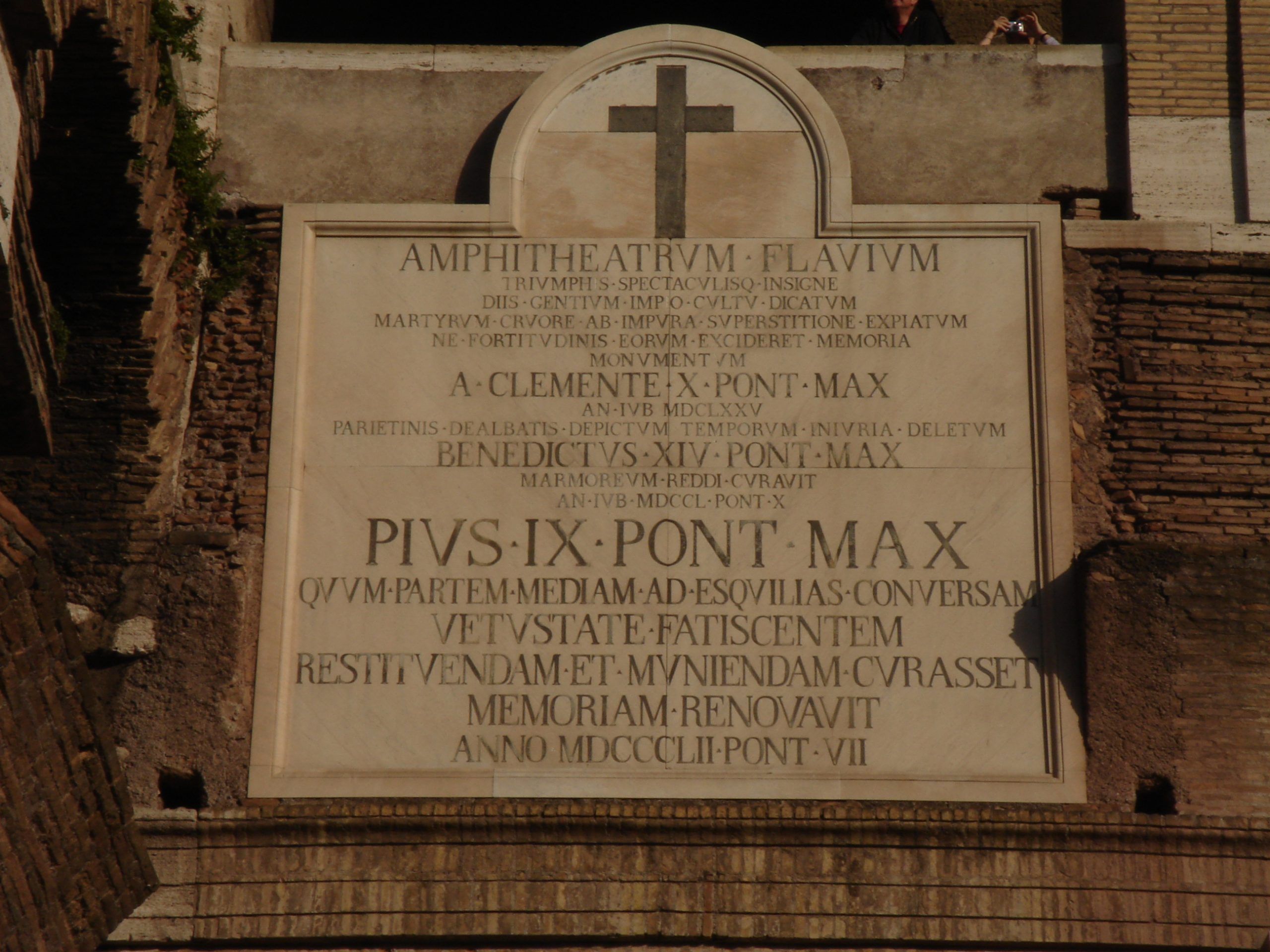 Latin inscription plaque mounted on the outer wall of the Colosseum, commemorating papal restoration efforts.