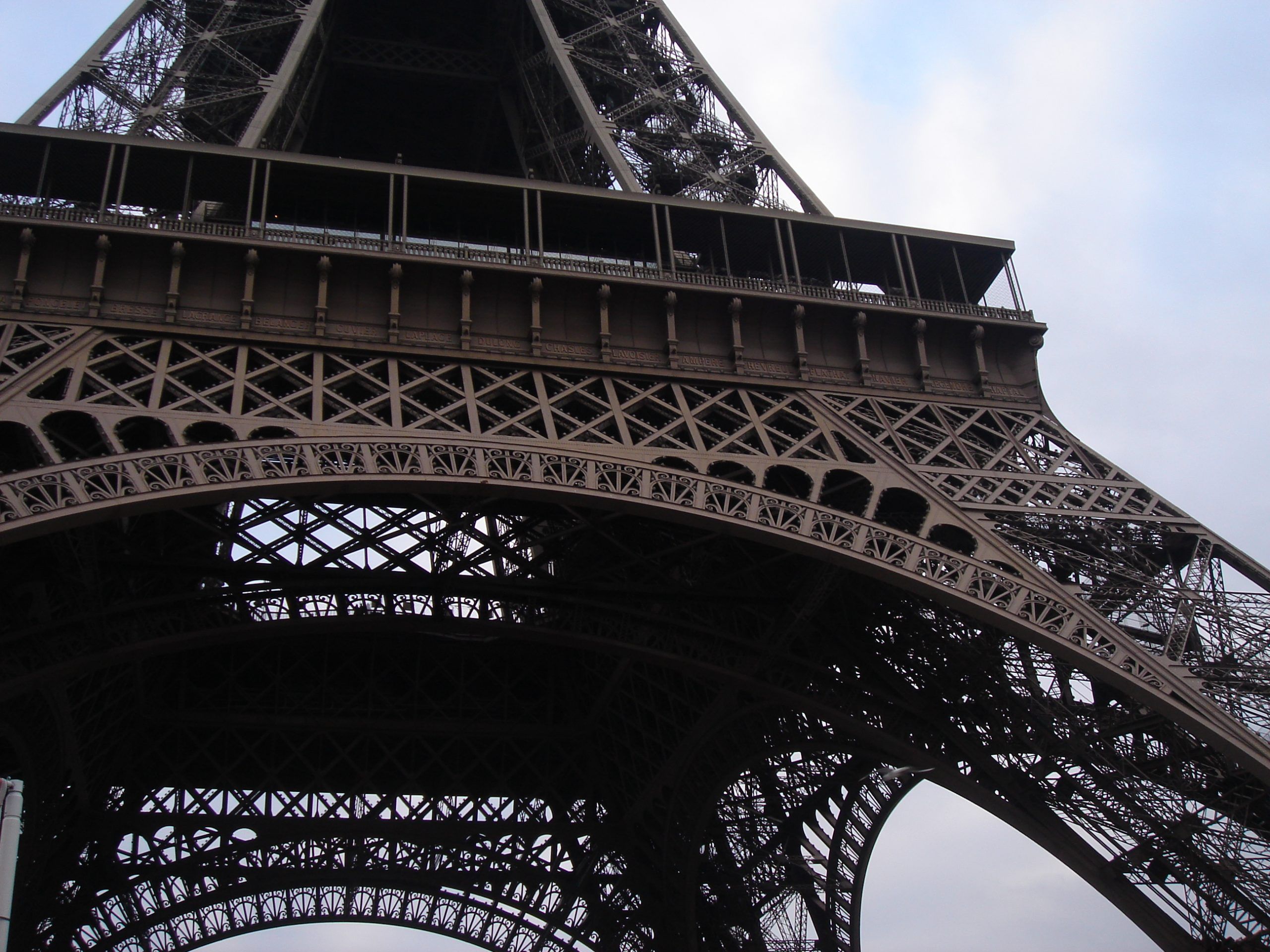Close-up upward view of the Eiffel Tower's iron latticework and first viewing platform.