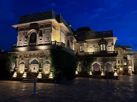 The ornately carved façade of Mandir Palace in Jaisalmer, Rajasthan, illuminated by warm lights against a deep blue evening sky