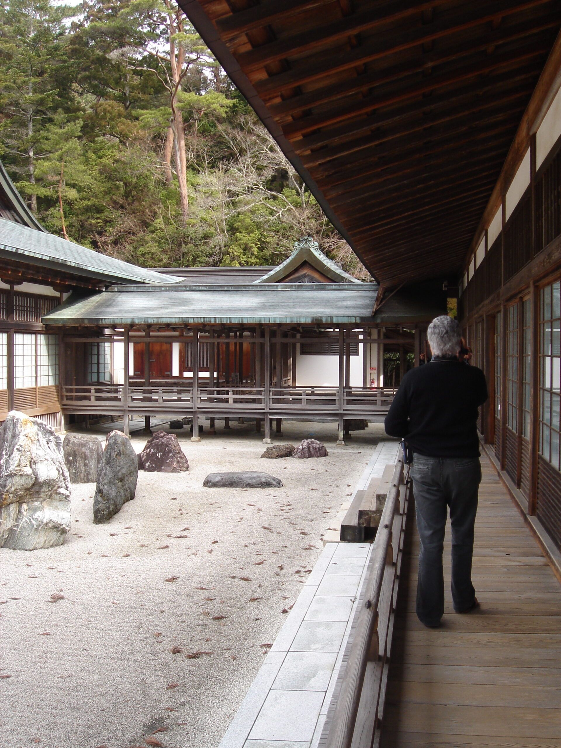 A man standing in the veranda of a Japanese temple looking into a rock garden.