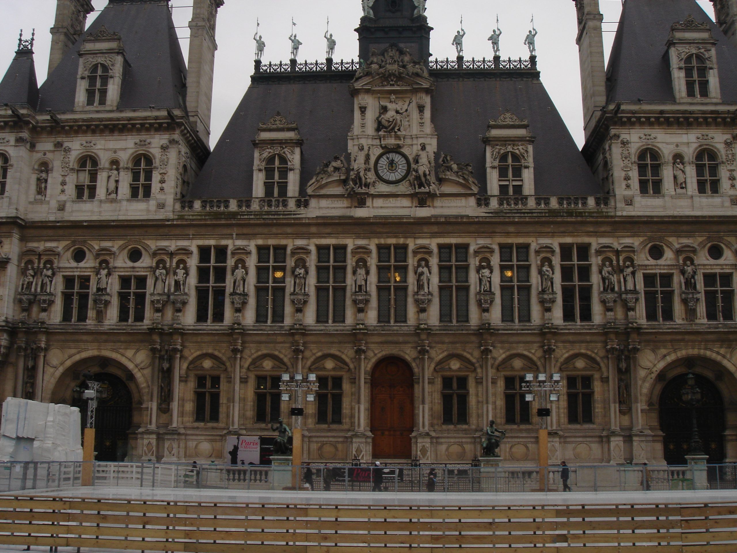Front façade of the Hôtel de Ville in Paris with statues and a skating rink.