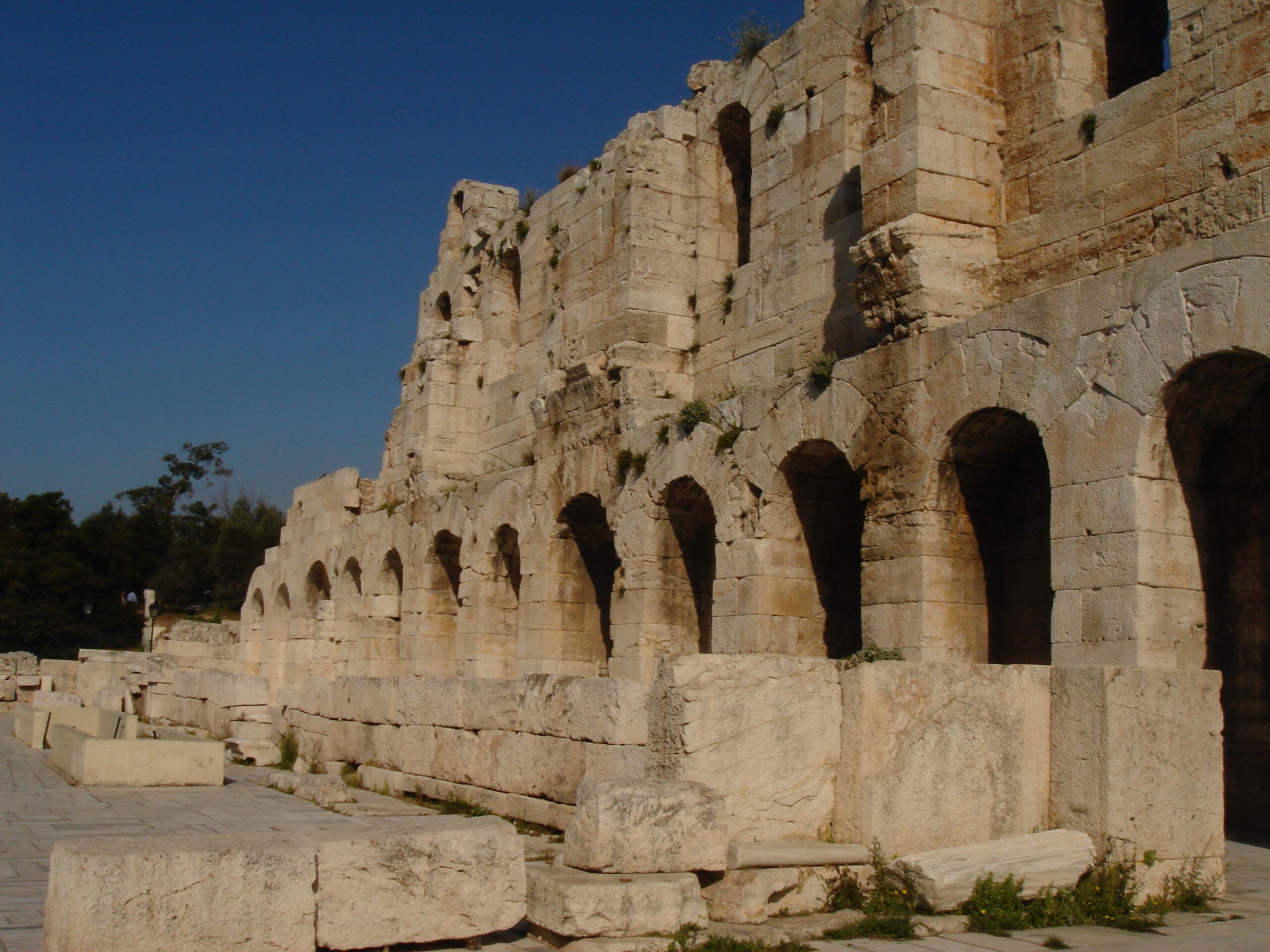 Close-up of the exterior wall of the Theatre of Herodes Atticus with rows of arches and weathered stone under a clear sky.