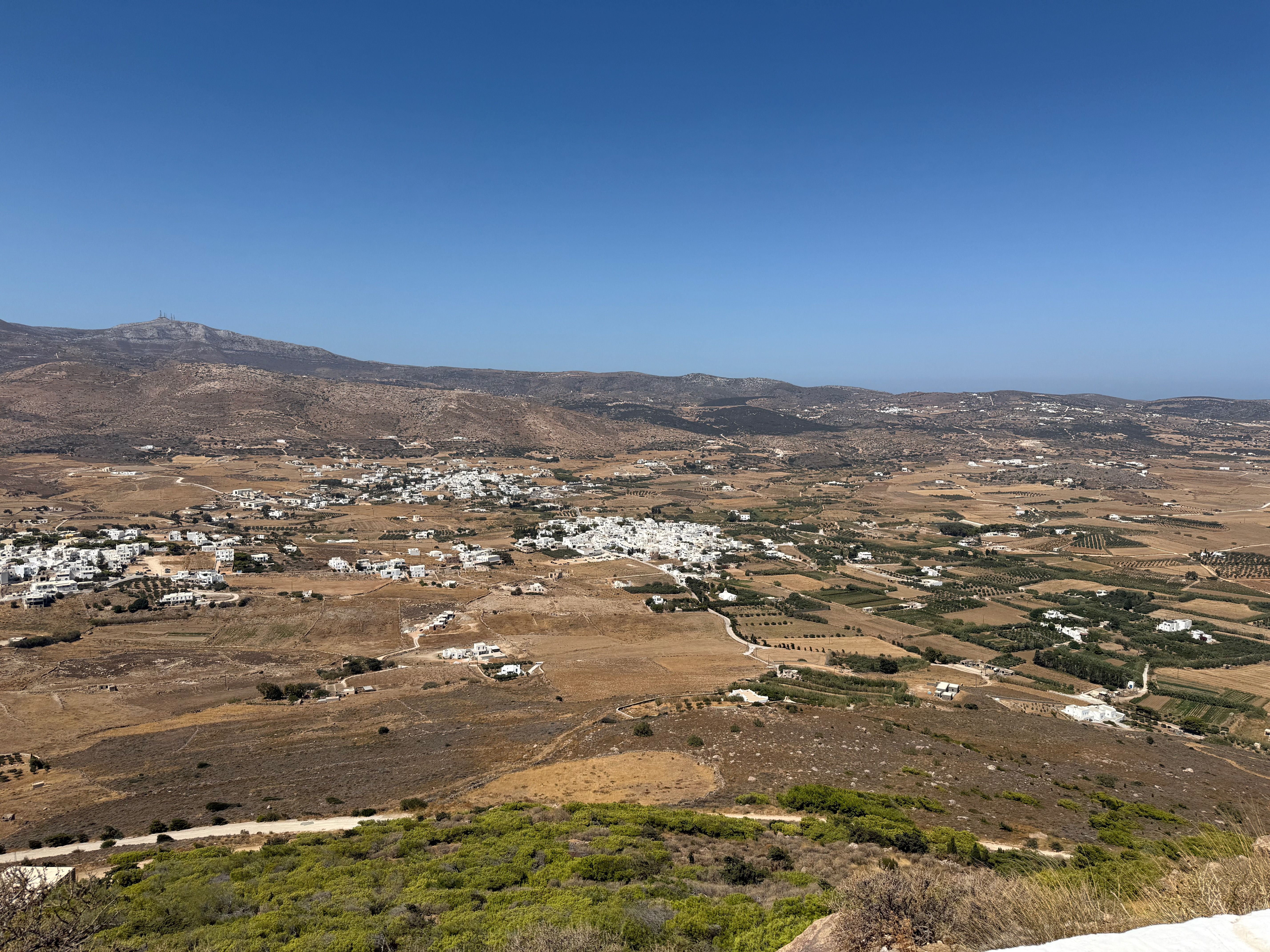 Another view from Agios Antonios. The same dry valley and the same distant mountain, but this time there are the white buildings of three small villages. To their right there is a patchwork of fields.