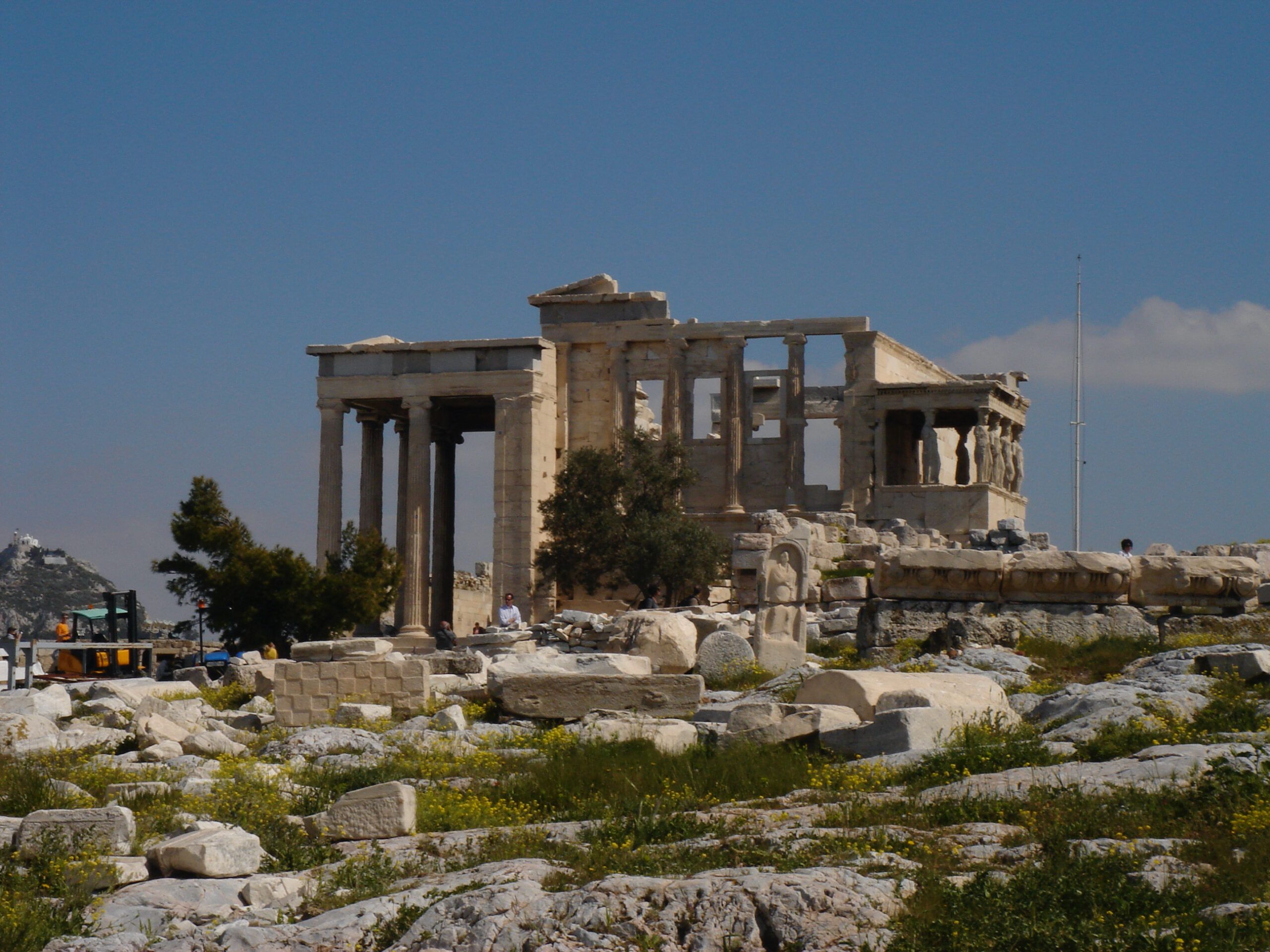 Archaeological ruins beneath the New Acropolis Museum, partially lit by sunlight and surrounded by modern glass walkways.