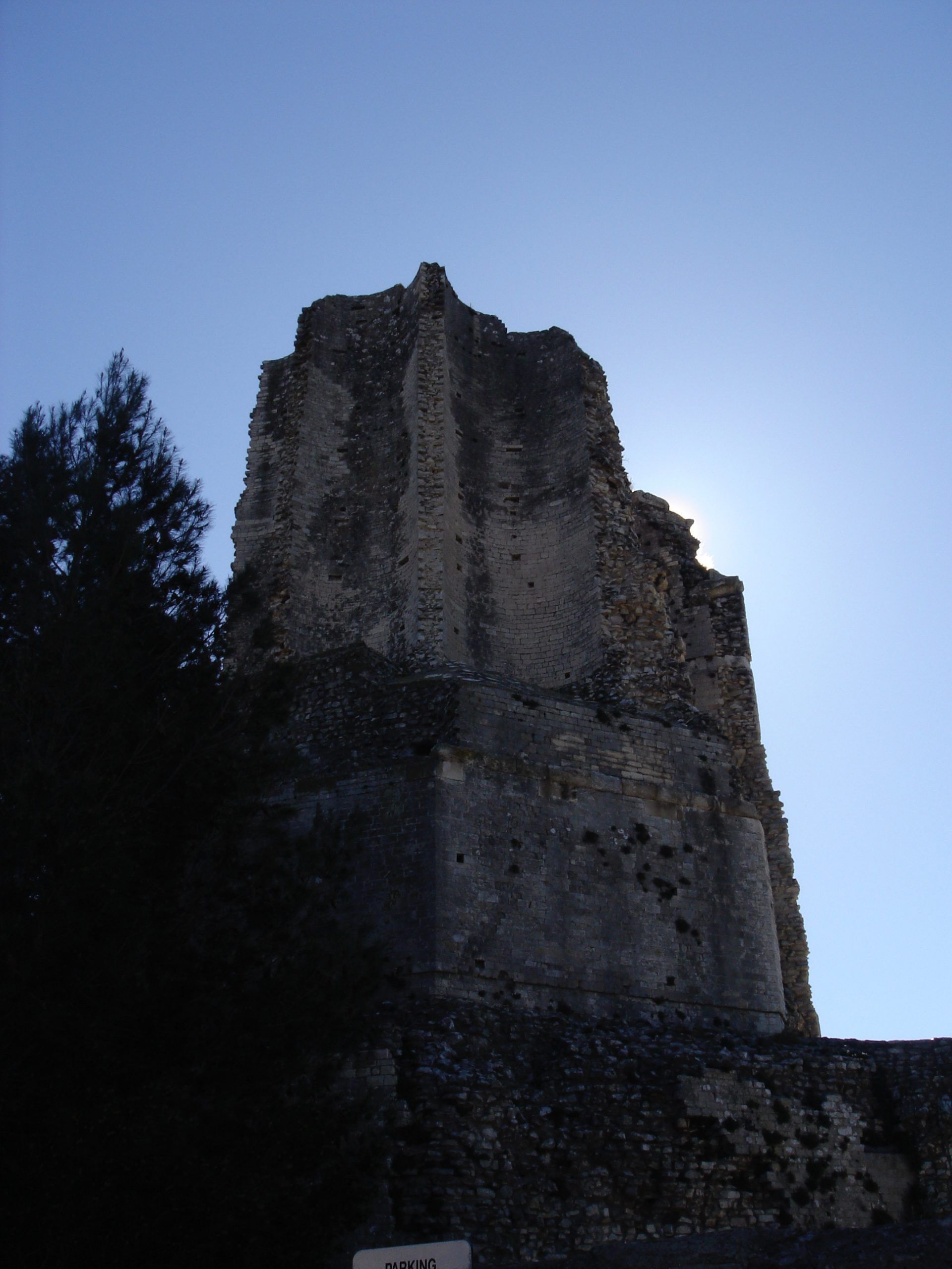 A tall stone tower in ruins, silhouetted against the early morning sky.