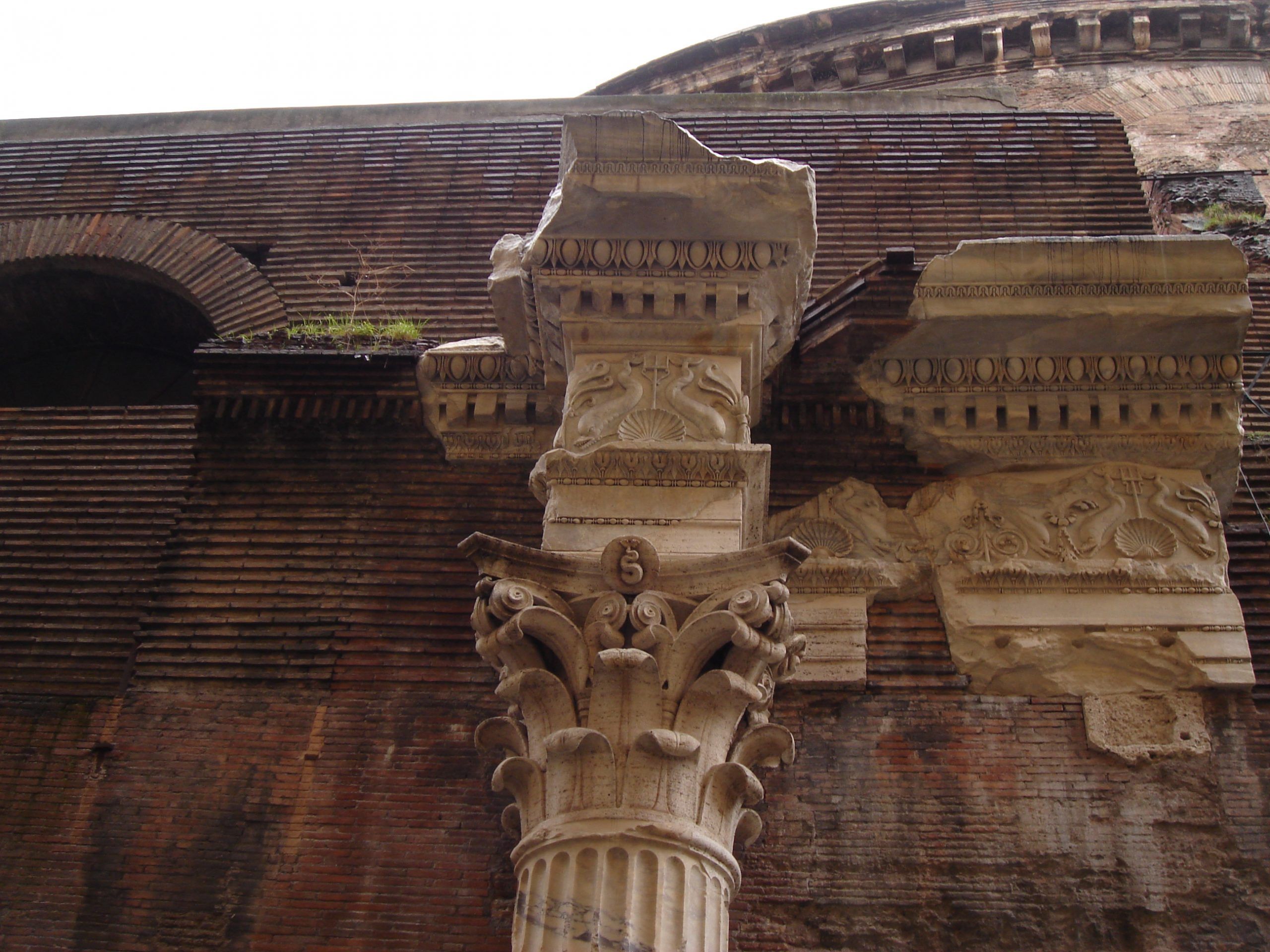 A detailed view of a broken Corinthian capital and decorative frieze on the Pantheon’s exterior wall.