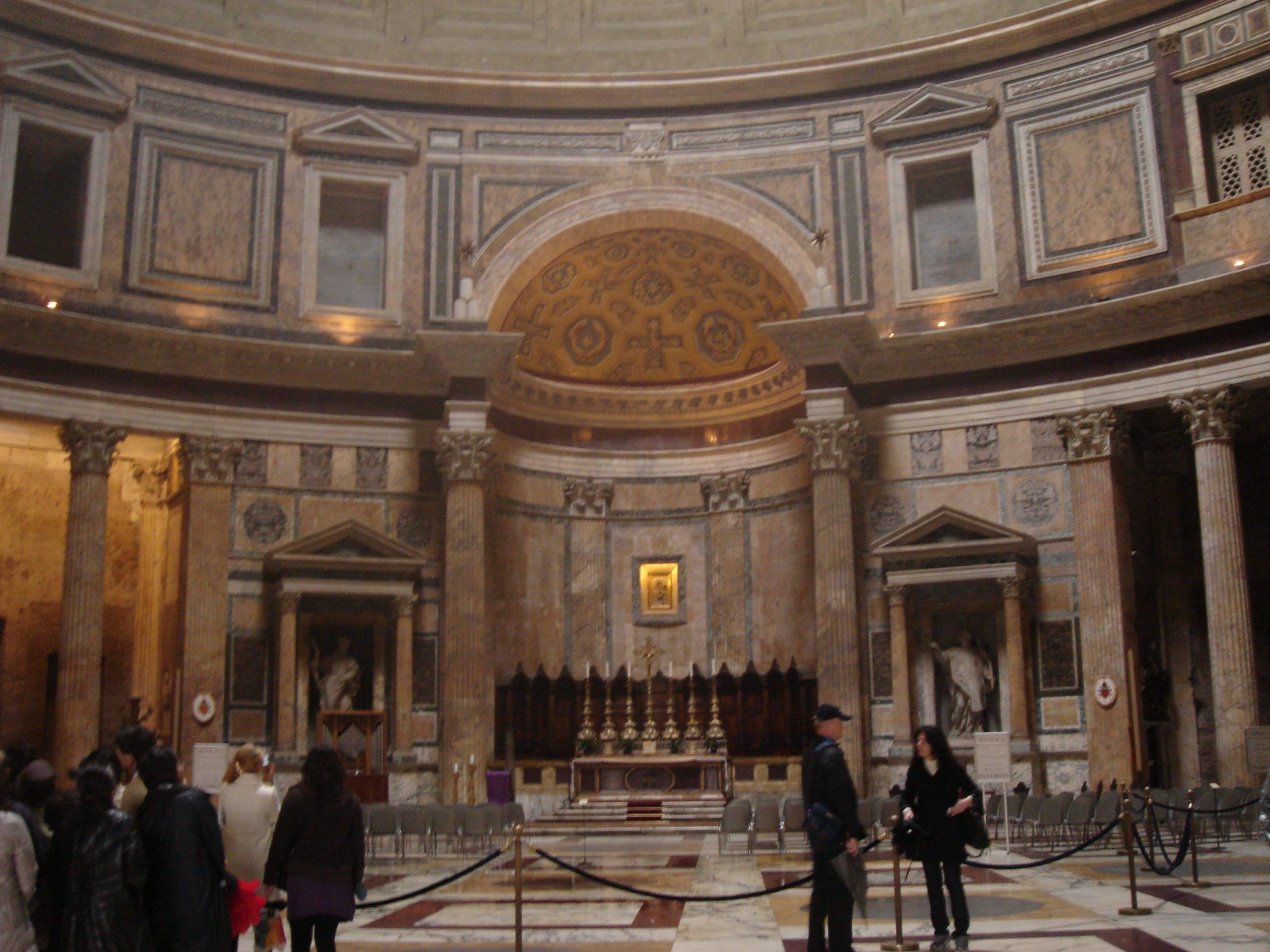 The richly decorated apse and altar inside the Pantheon, with visitors in the foreground.
