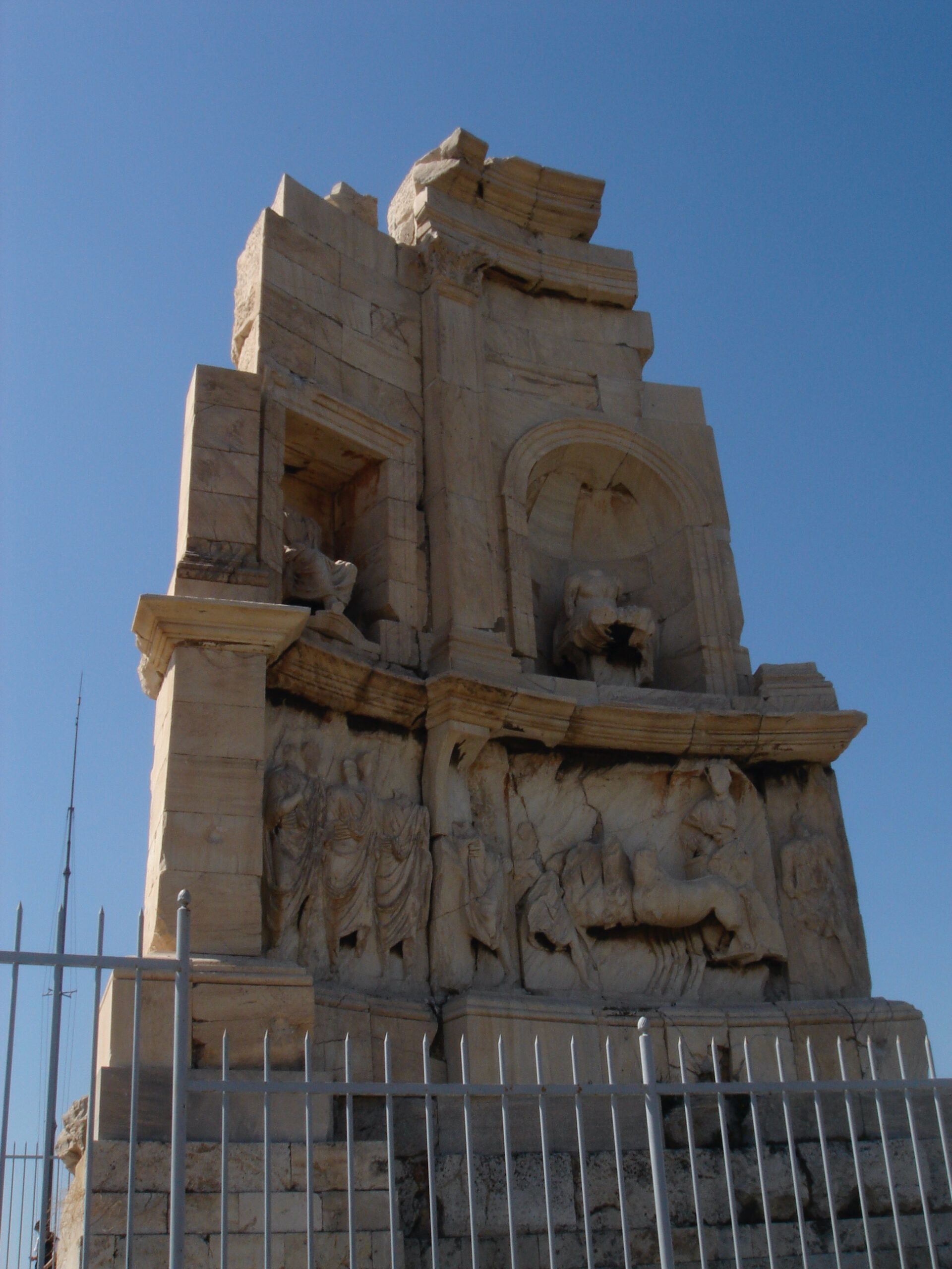 Close-up of the Monument of Philopappos, showing detailed classical relief carvings and stone architecture.