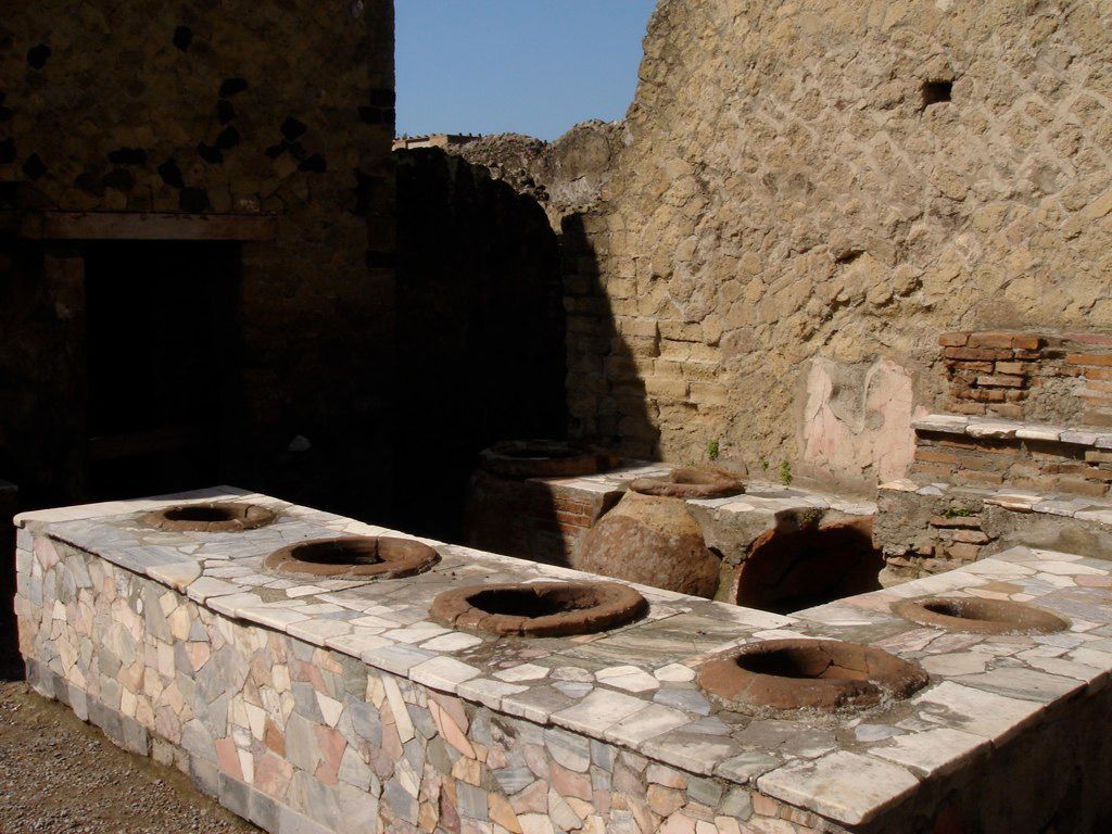 Marble-clad counter of a Roman thermopolium in Herculaneum, with embedded dolia used for serving hot food and drinks.