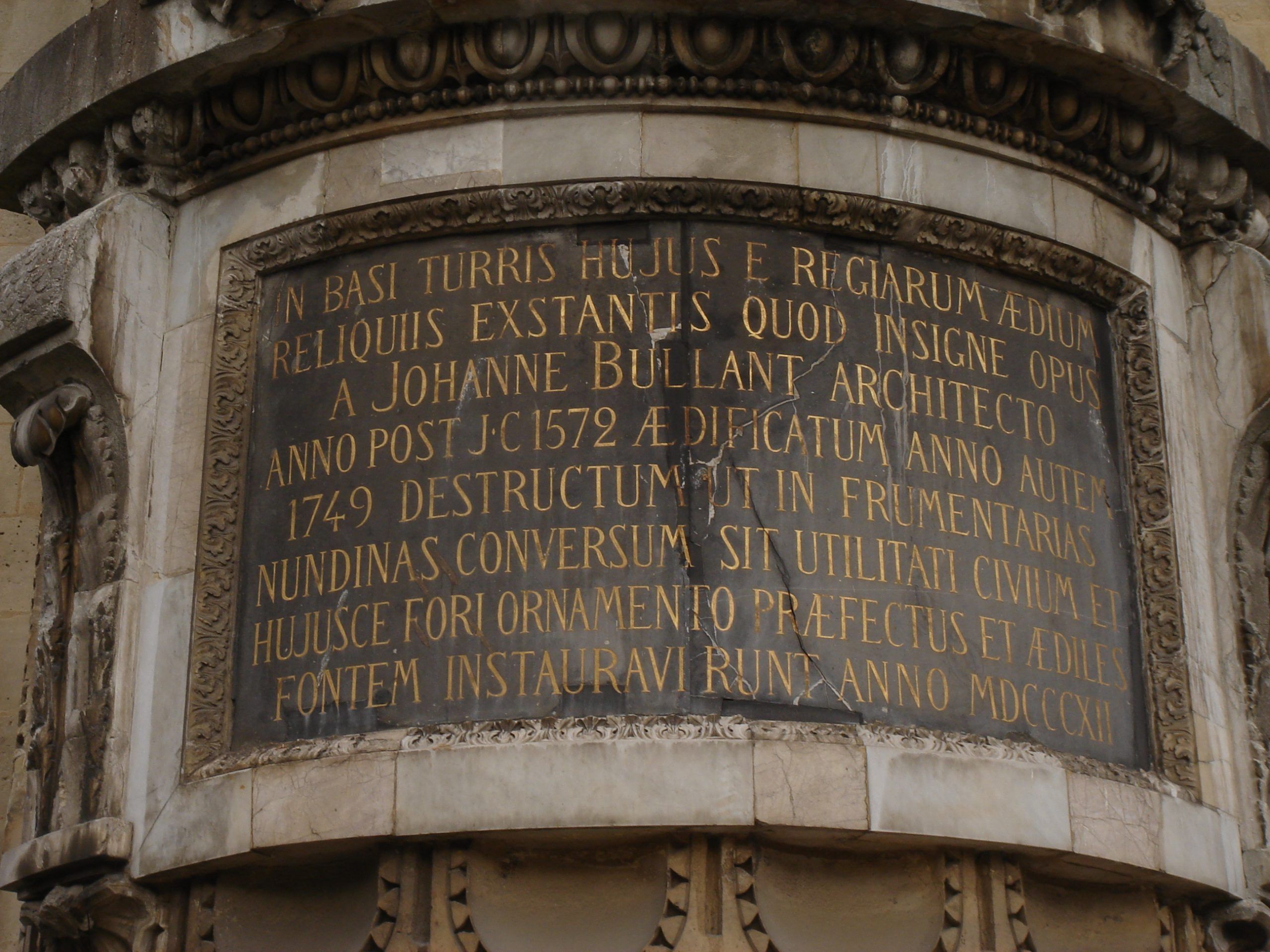 Close-up of a Latin inscription plaque mounted on an aged stone wall.