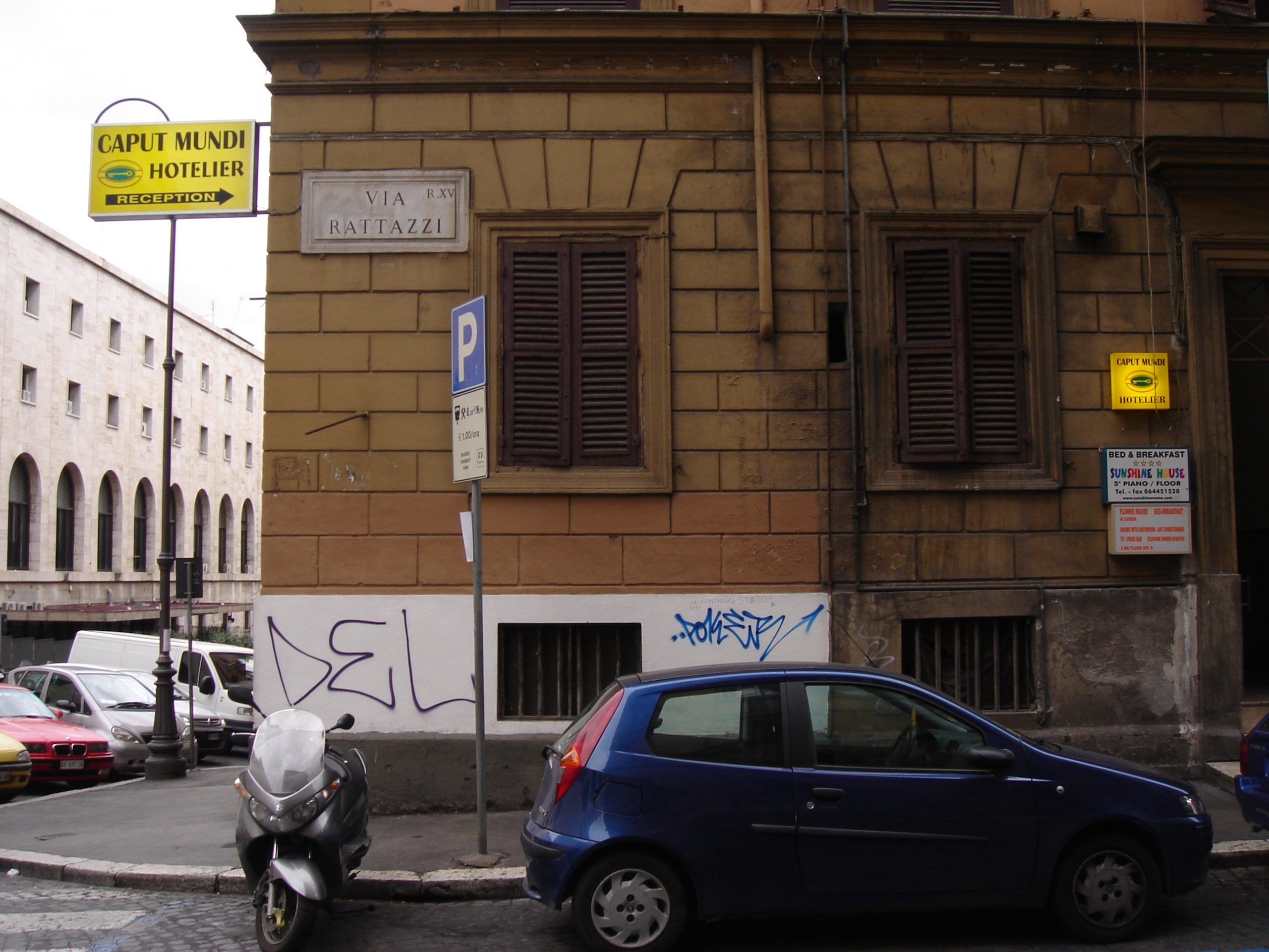 Street view of a Roman corner building with a sign for the Caput Mundi Hotelier and a street sign for Via Rattazzi.