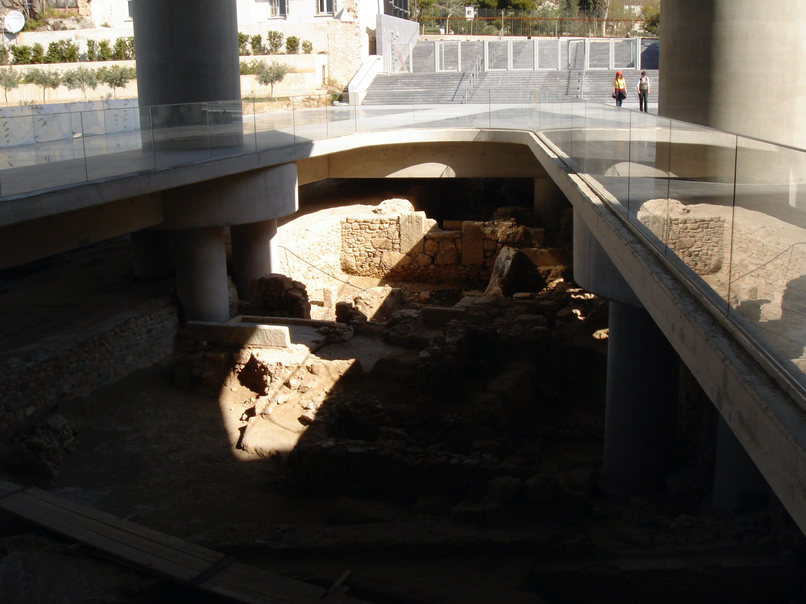 Exposed ancient foundations under the New Acropolis Museum, with structural remains visible beneath elevated glass platforms.