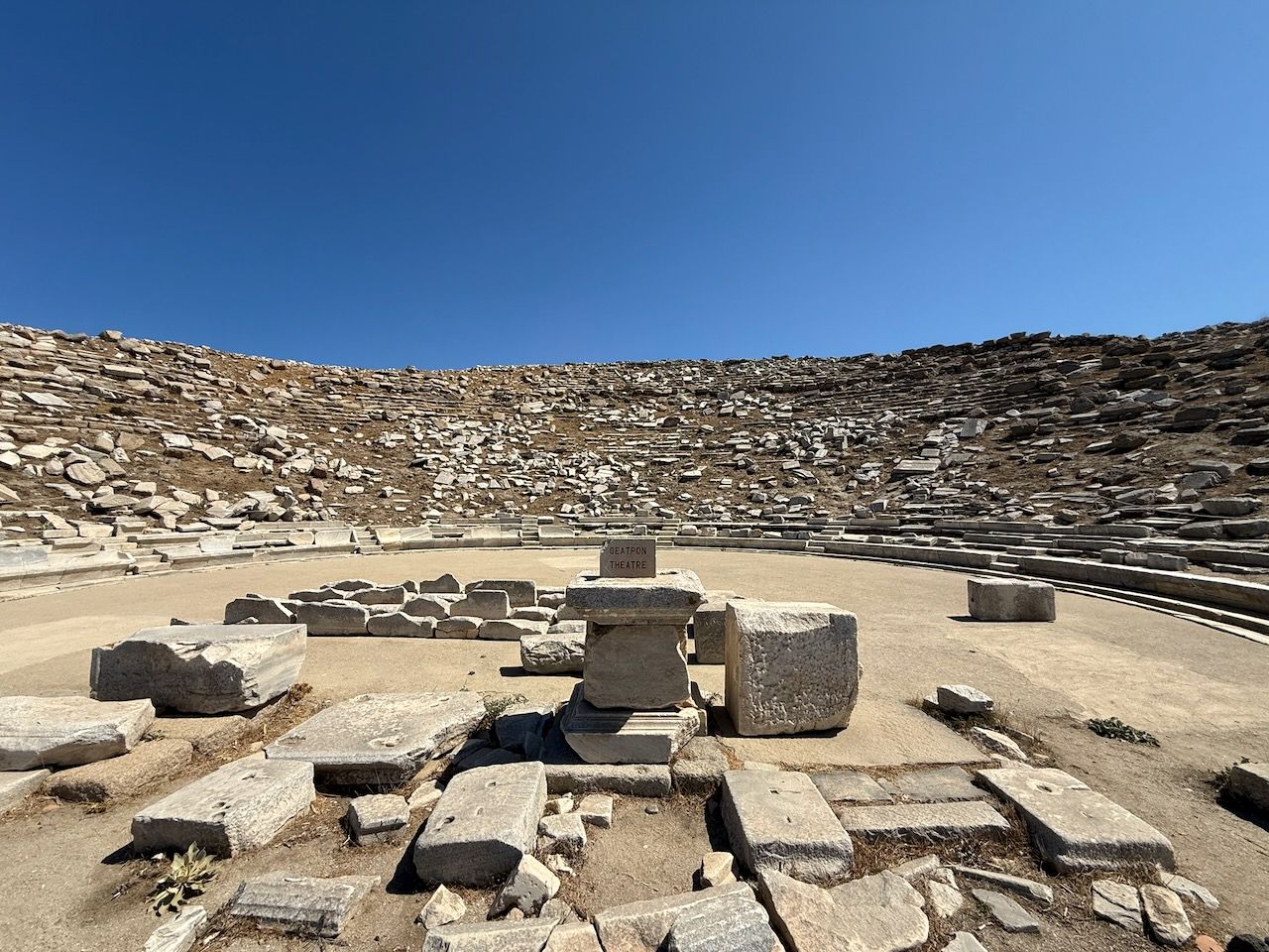 The theatre on Delos, looking out across the orchestra to the seating area. There are remnants of high back chairs in the front row, but most of the seating is rubble now.