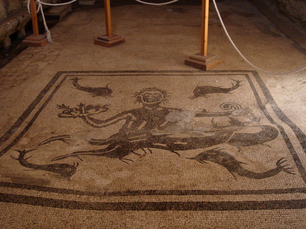 Mosaic panel in Herculaneum depicting a marine scene with a god or hero surrounded by dolphins, executed in black and white tesserae.