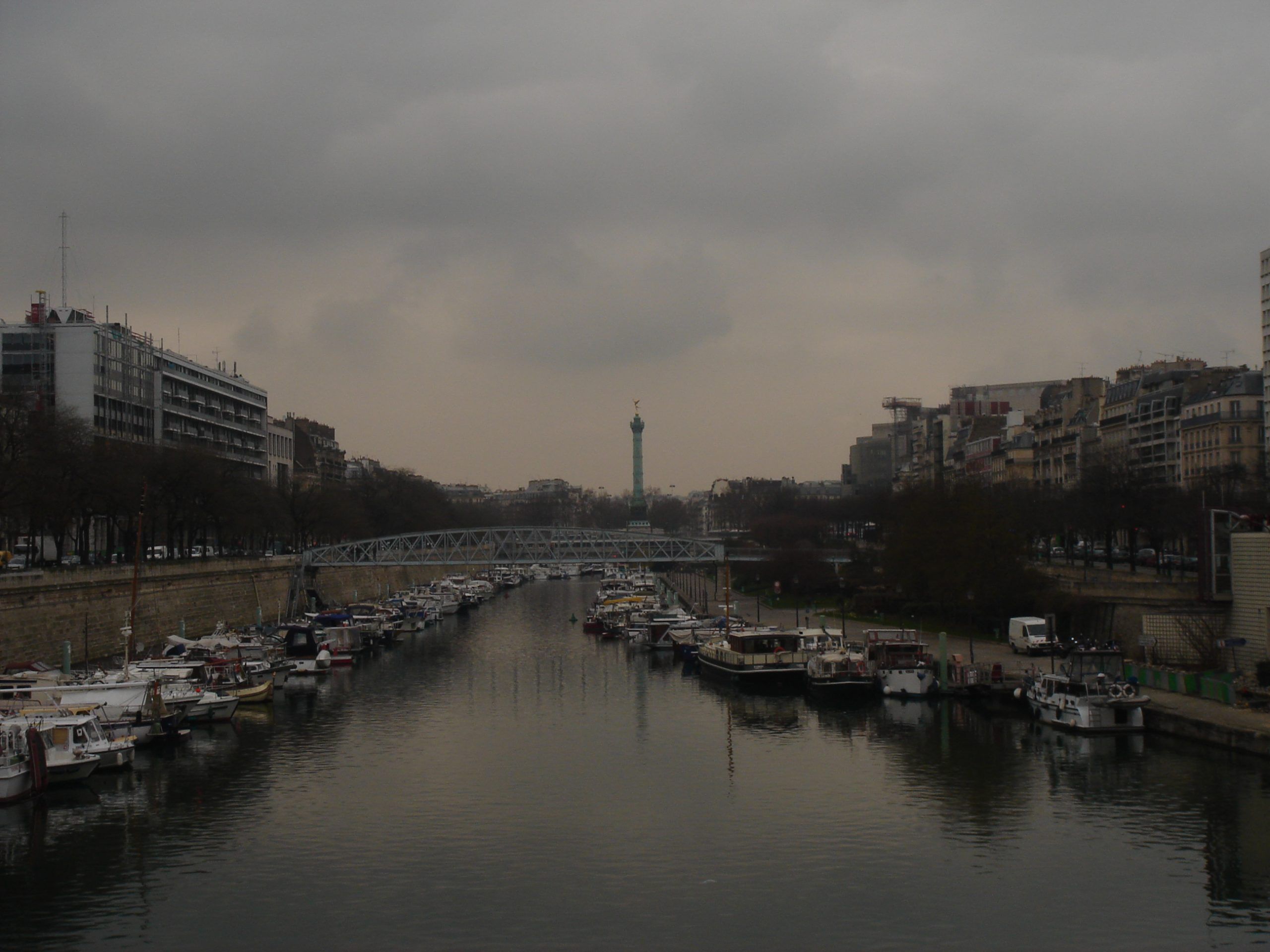 Boats moored in the Port de l'Arsenal canal with the July Column in the distance.