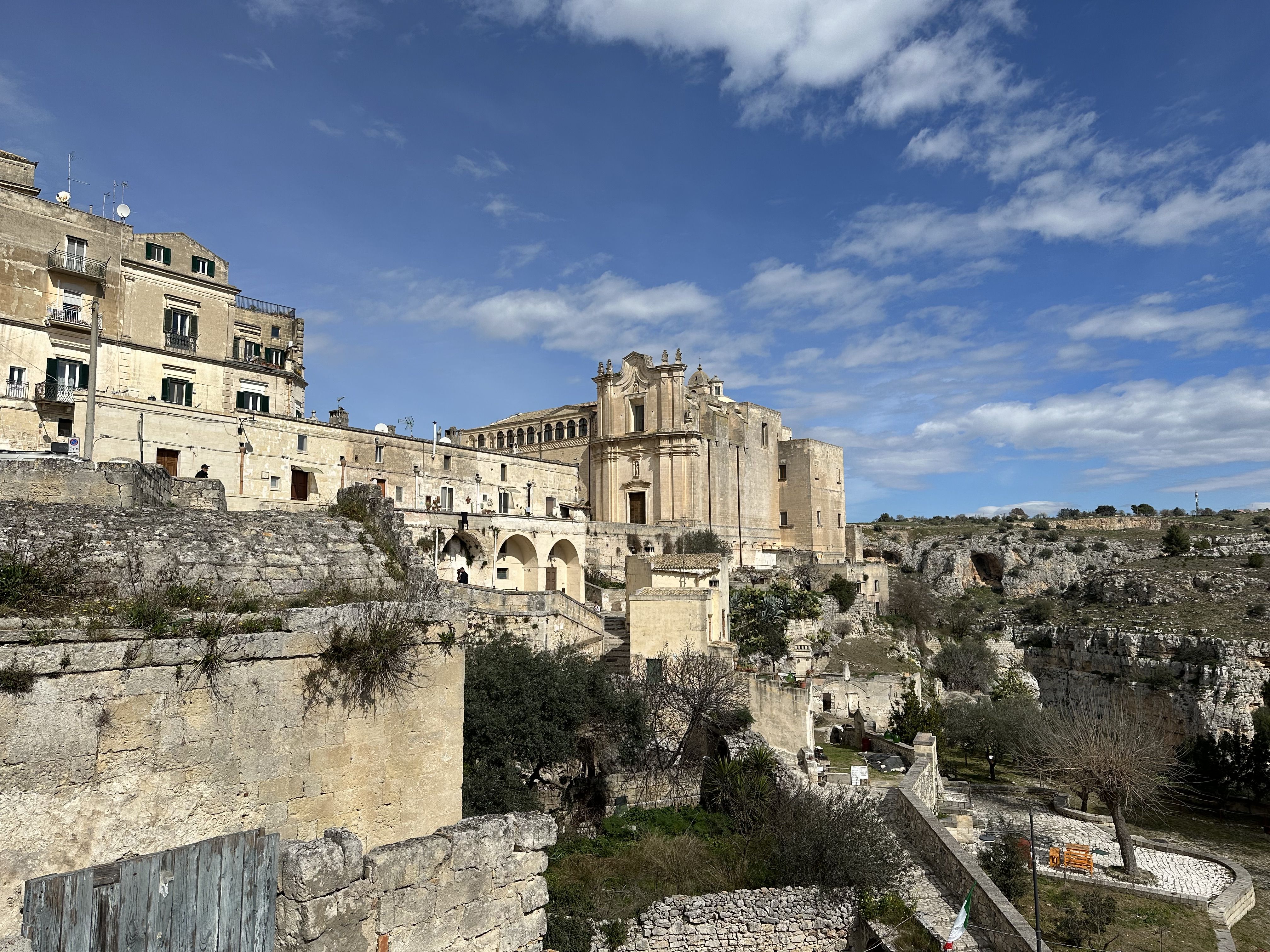 Church of Sant’Agostino in Matera with its ornate Baroque façade, set above rocky slopes and surrounded by ancient dwellings.