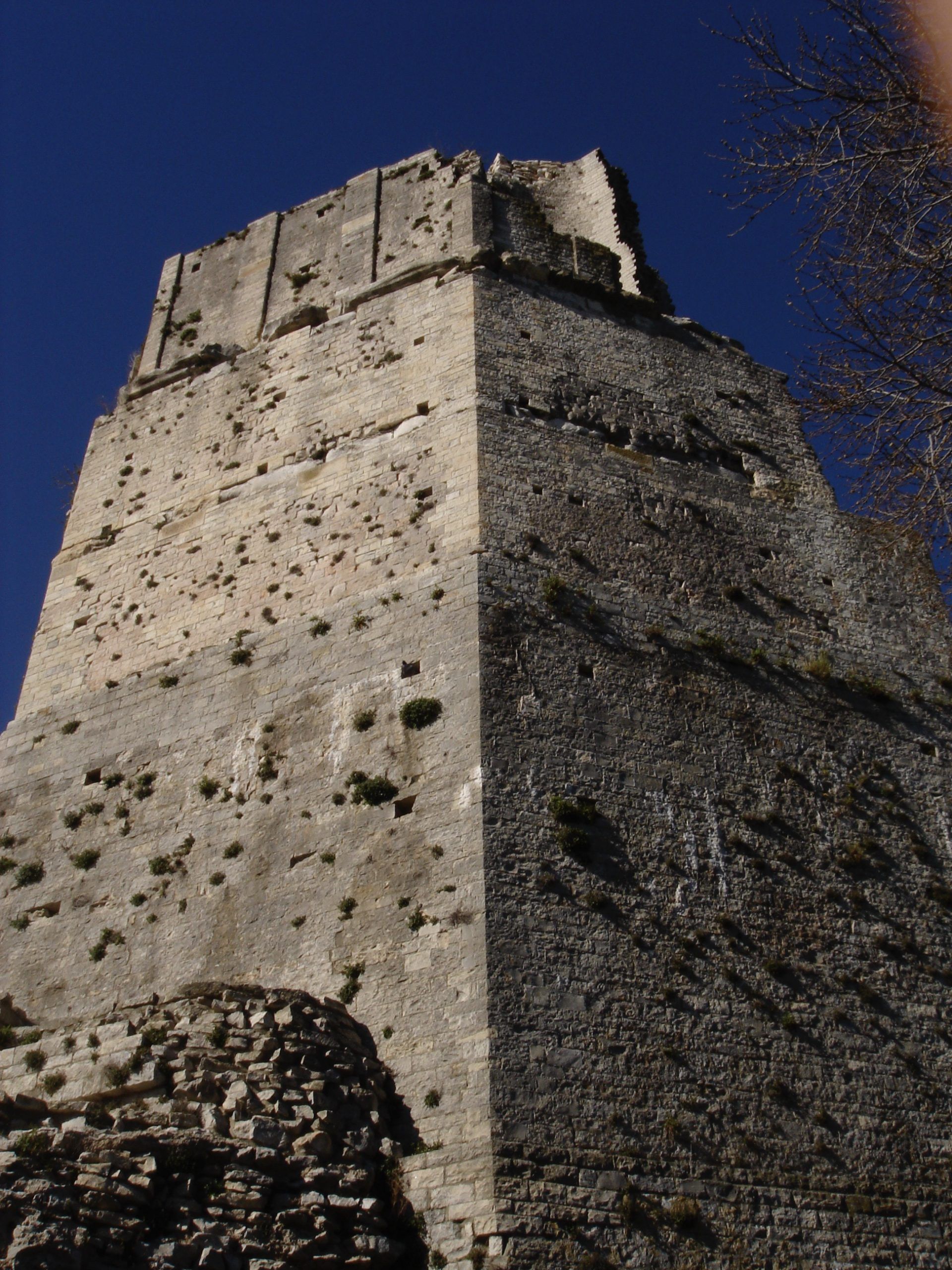 Looking up at the weathered stone surface of the Tour Magne in Nîmes, with visible ancient damage.