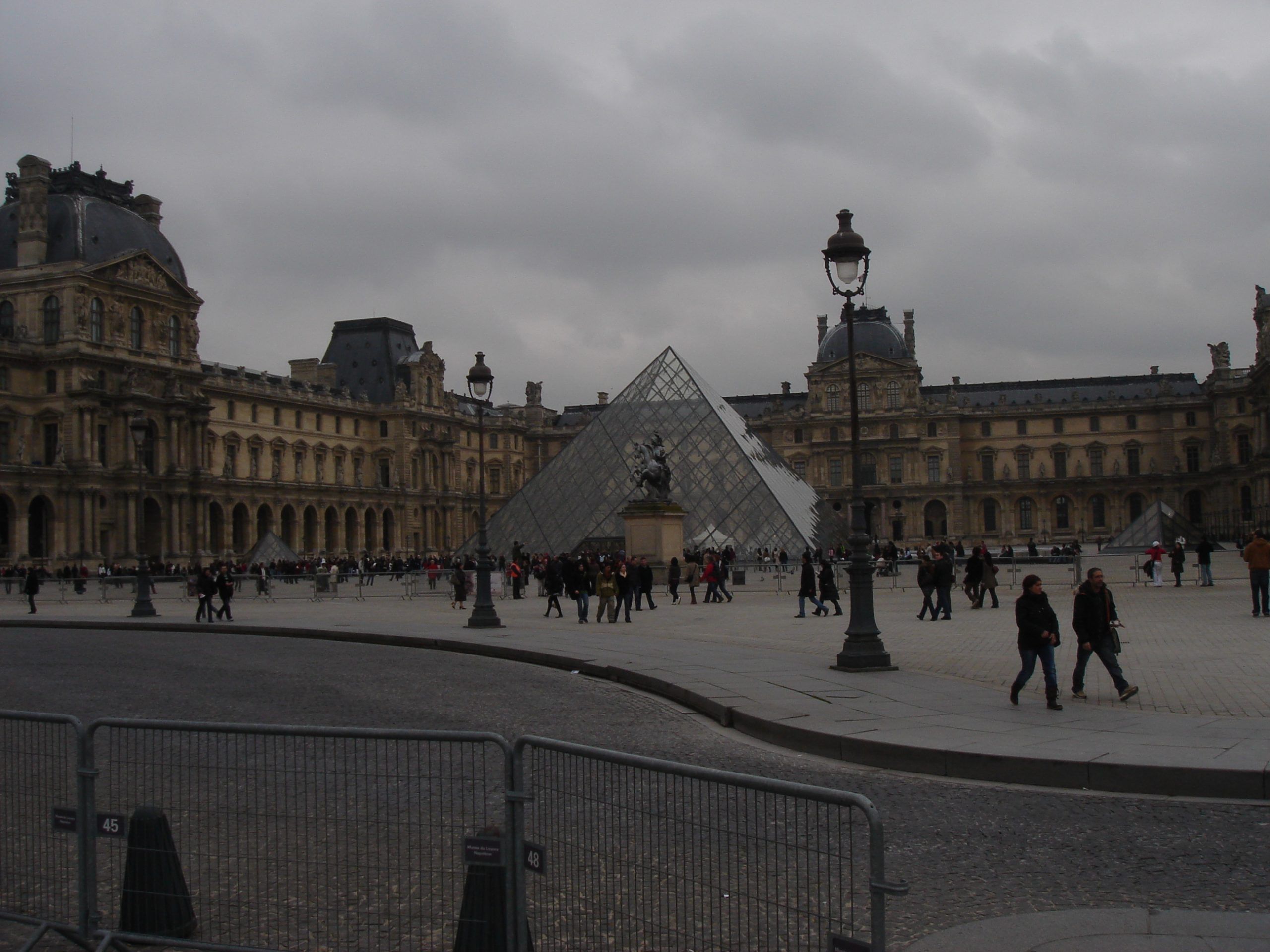 The Louvre’s Cour Napoléon with glass pyramid entrance and surrounding buildings.