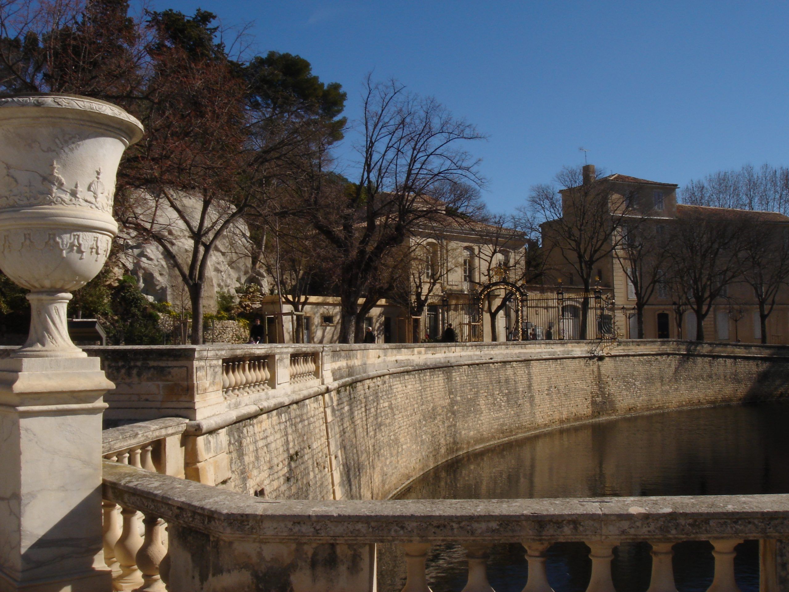 Curving balustrade and ornate urns beside the water in the formal park in Nîmes.