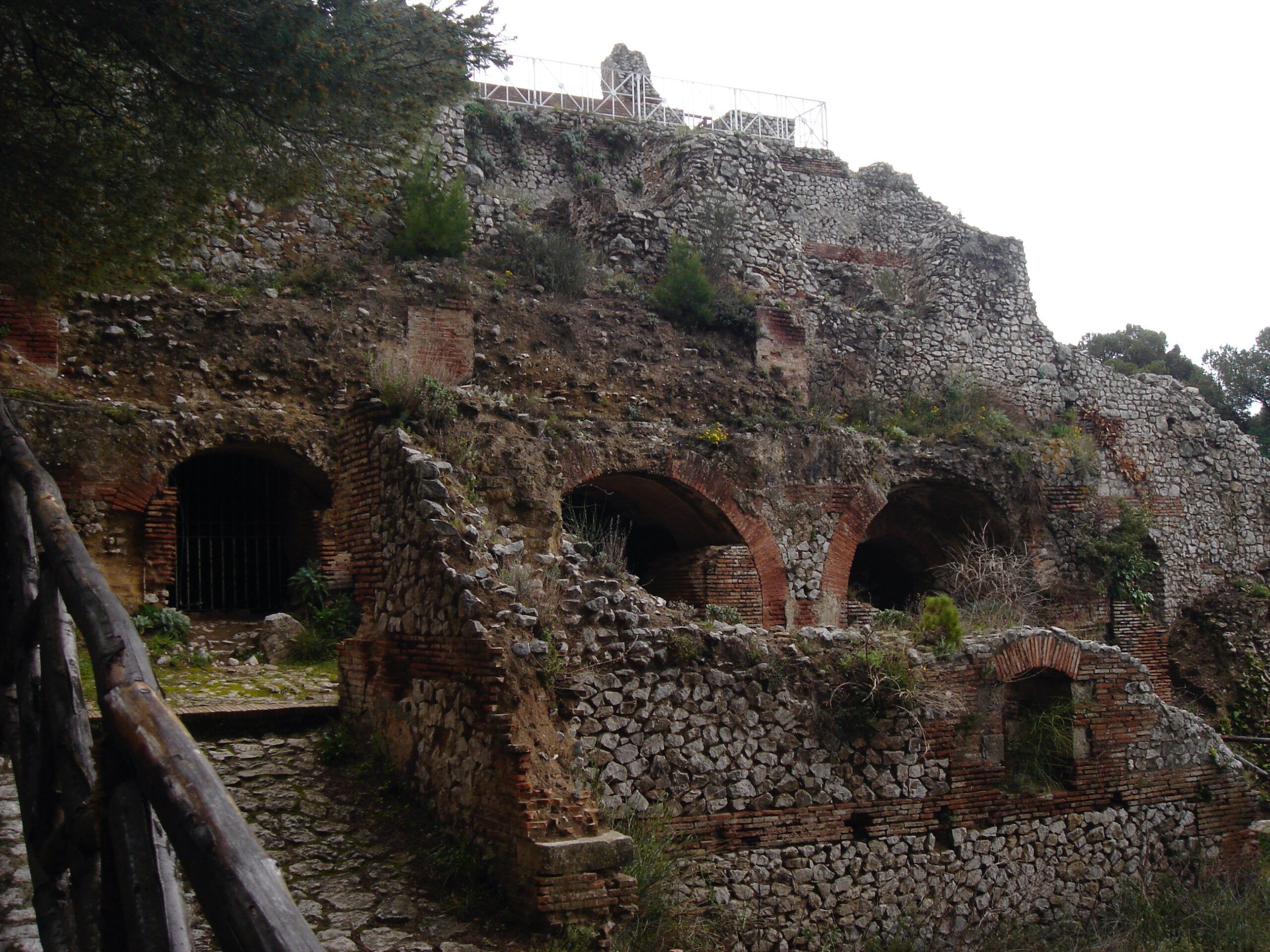 Sweeping view of the mountainous island landscape from Villa Jovis, with dense green trees and white buildings below.