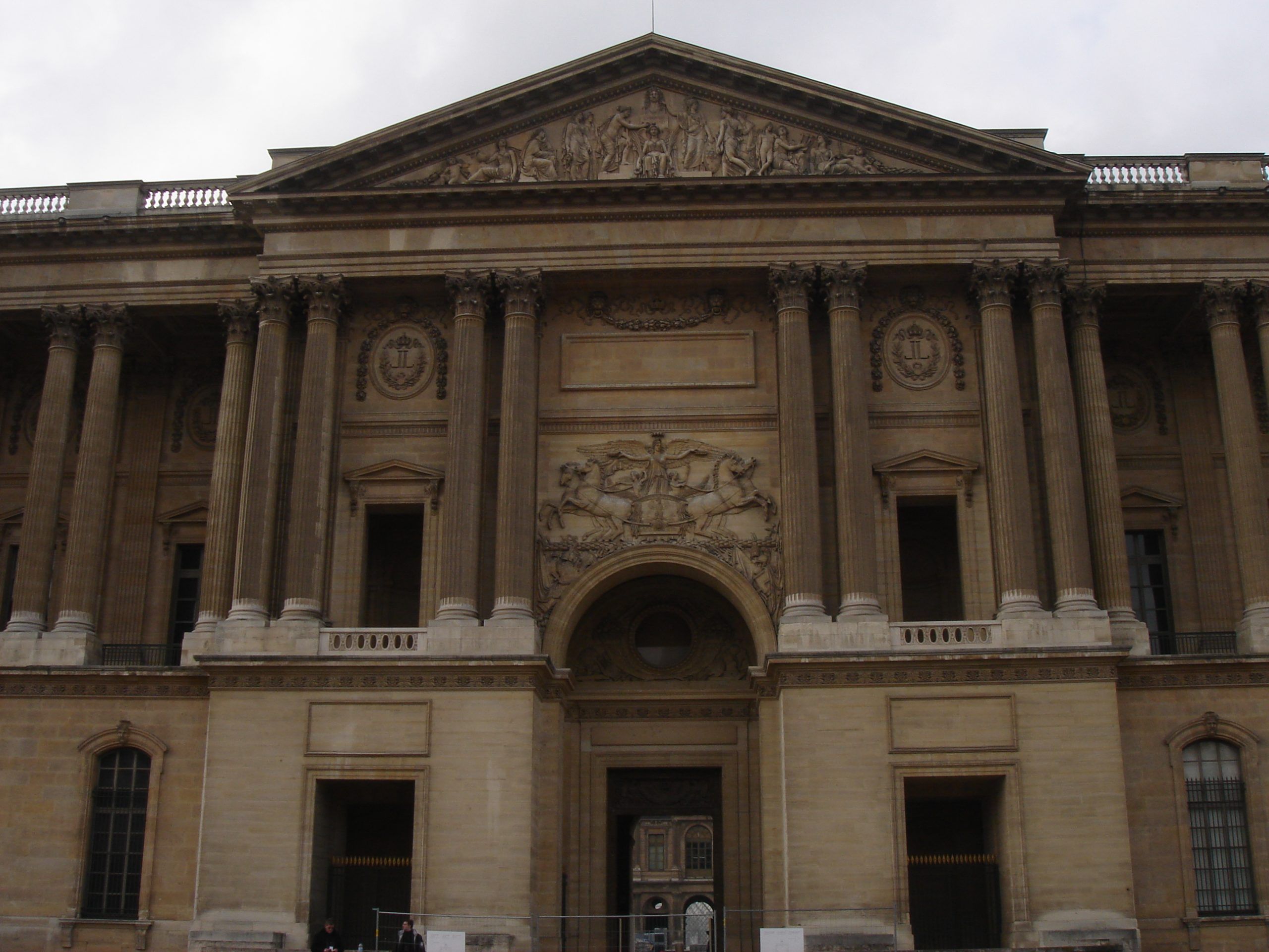 Classical pediment and columns of a Louvre building façade with sculpted reliefs.