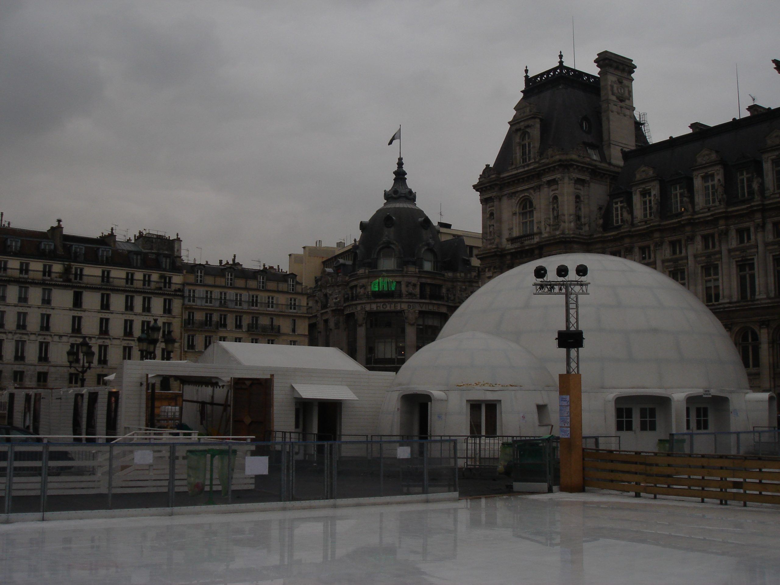 Ice rink and large white domes in front of the Hôtel de Ville in Paris, with historic buildings behind.