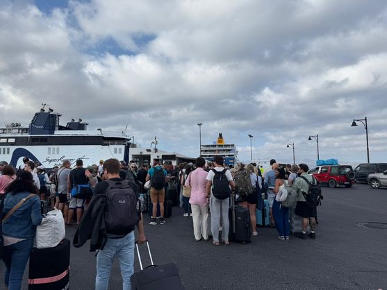 It's a marble rectangle, over two metres high, the remains of an unfinished temple. It stands on a rocky hillside on the coast; it's surrounded by marble blocks. Through it the white blocky buildings of the town of Naxos are visible, as well as  dark, sunlit clouds.