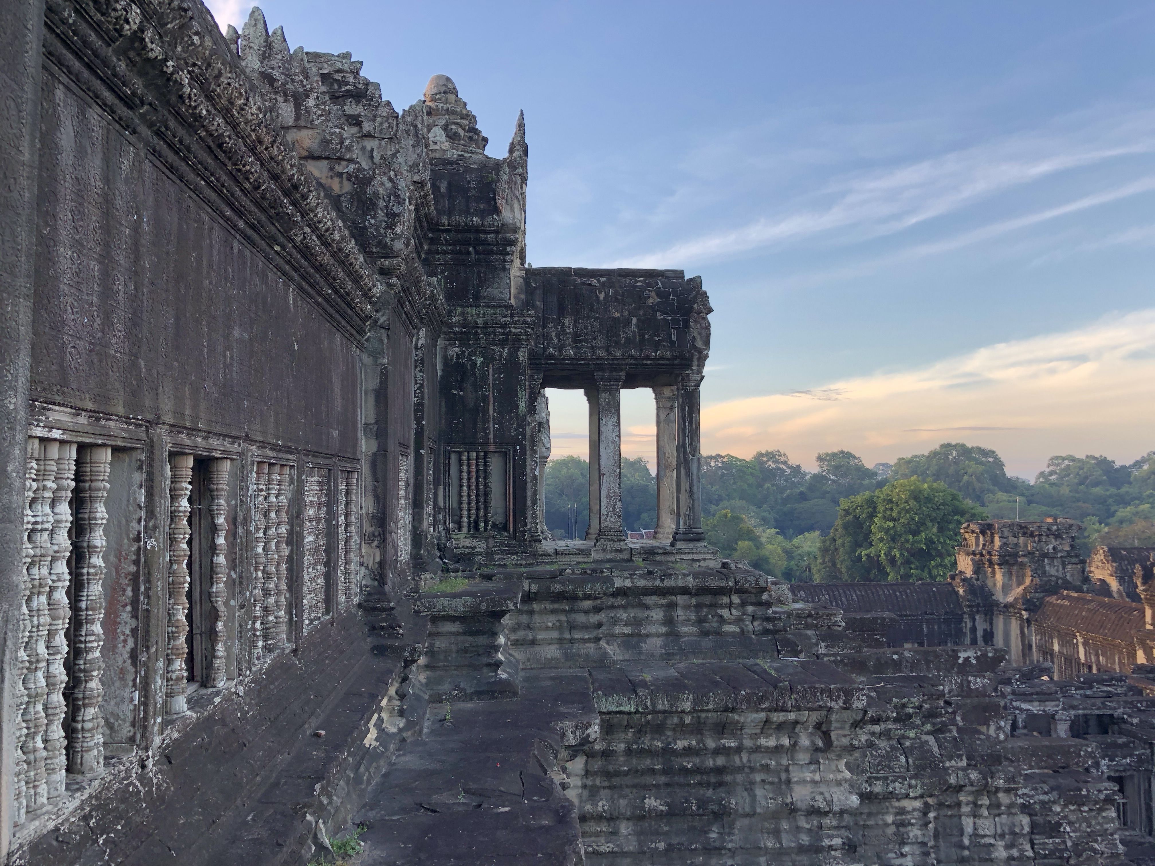 Looking along the wall of some kind of quadrangle. A pillared balcony  juts out from the wall. The walls are covered with spiral pillars, and everything is stained white. 