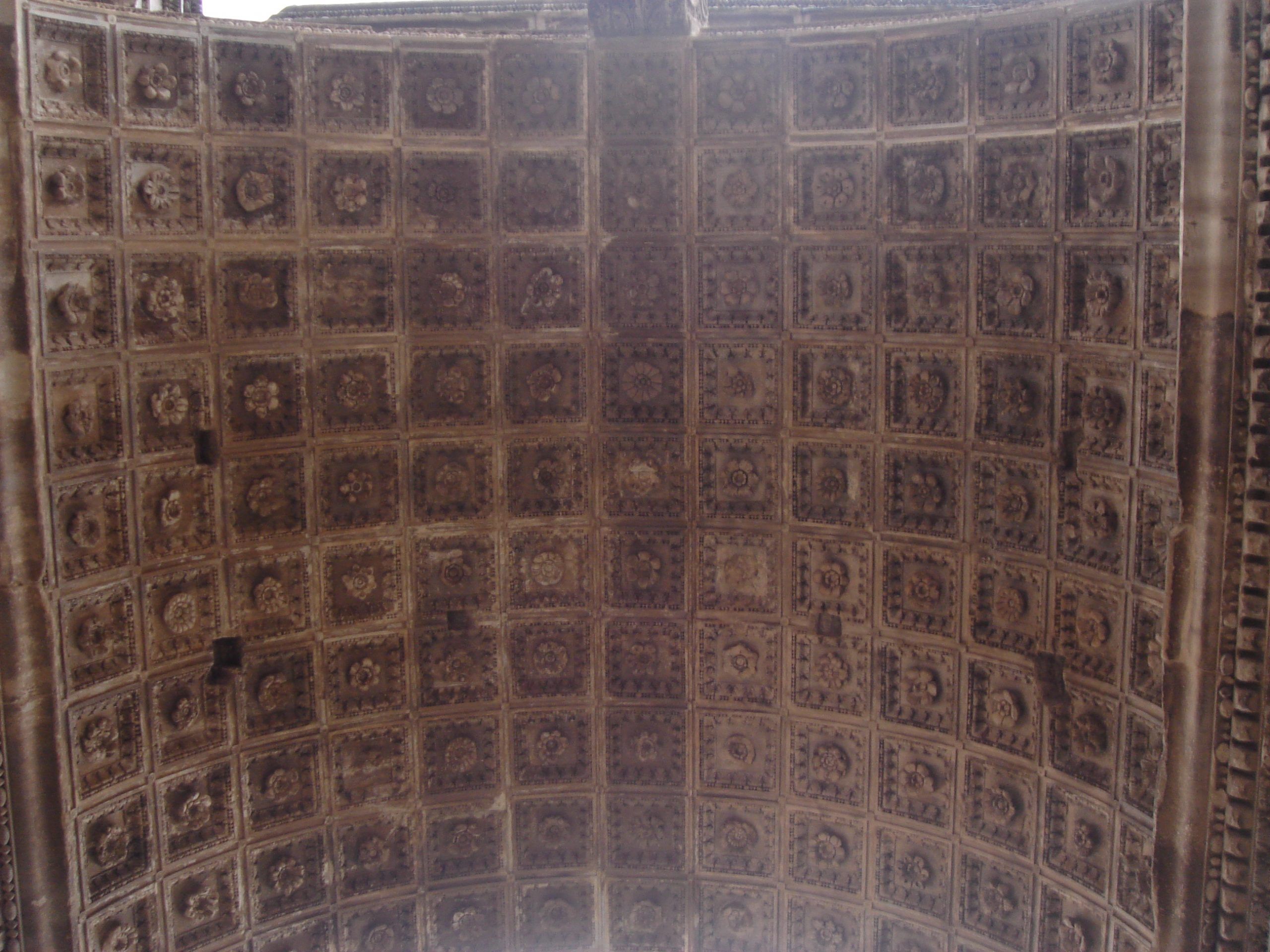 Ornate coffered ceiling of a Roman triumphal arch, richly decorated with square floral reliefs in deep recesses.